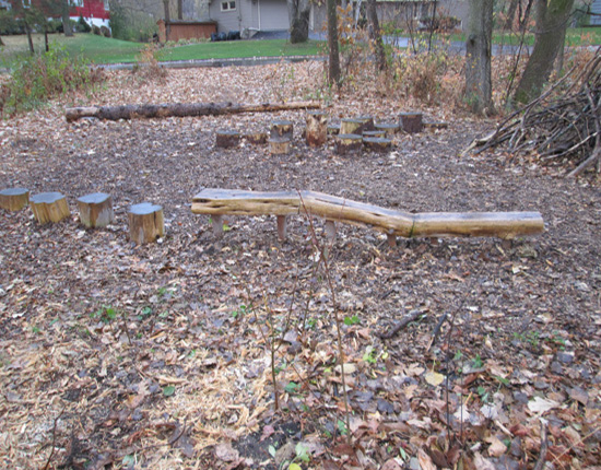 A nature play area with stumps and a balance beam for preschoolers at St. David's Center School Forest, Minnetonka.