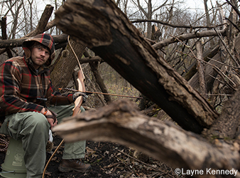 photo of traditional archer concealed in a ground blind made of natural materials